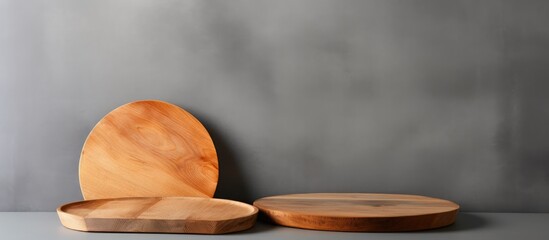 Three wooden plates crafted from natural material are displayed on a table against a gray wall. They are ready to be filled with delicious cuisine made from fresh ingredients