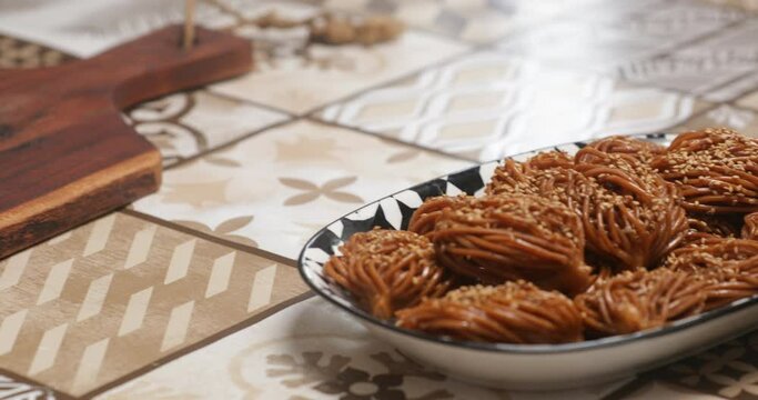 A feast for the eyes and palate, bouchnikha graces the plate in a harmonious arrangement, each piece a blend of sweet honey, crunchy sesame seeds, and tender pastry