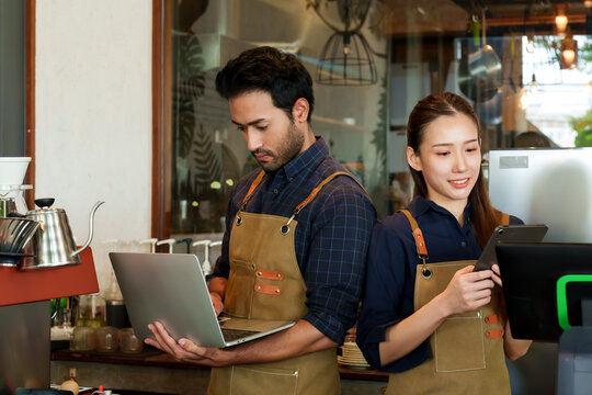 business couple cafe owner Asian woman standing tablet checking orders bakery goods drinks  cafe men of various nationalities checking cafe sales notebooks Behind  counter coffee maker cash register.