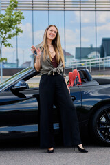 In a display of triumph and achievement, a woman poses next to her brand-new, high-end convertible,...