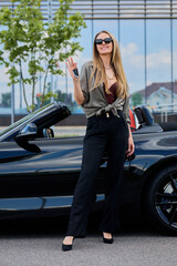 With keys in hand and a satisfied smile, a woman owning an expensive convertible