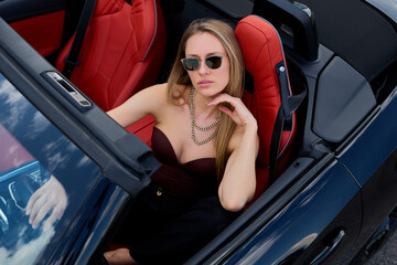 Woman exudes confidence as she drives her convertible through sun-kissed landscapes, embracing the...