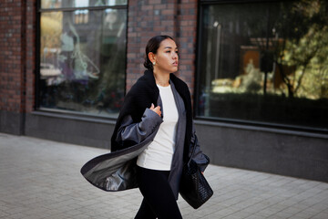 Stylish fashion woman strolls down the street in multilayer clothes oversized blazer, black...
