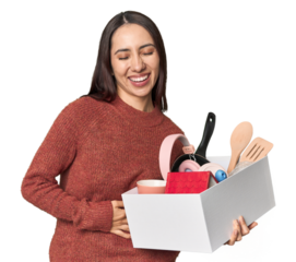 Caucasian young woman holding a box for moving on studio background laughing and having fun.