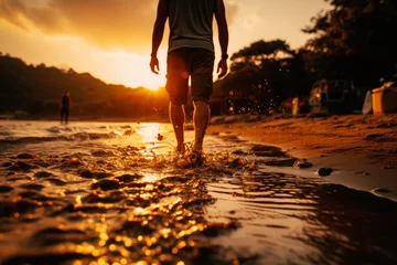 Poster Man walks along the sandy beach as the sun sets behind him. Person running toward the water at sunset beach © Lazy_Bear