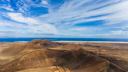 View over a desert tunring into the ocean with a cloudy blue sky
