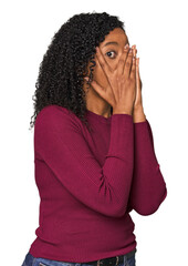 African American woman in studio setting blink through fingers frightened and nervous.