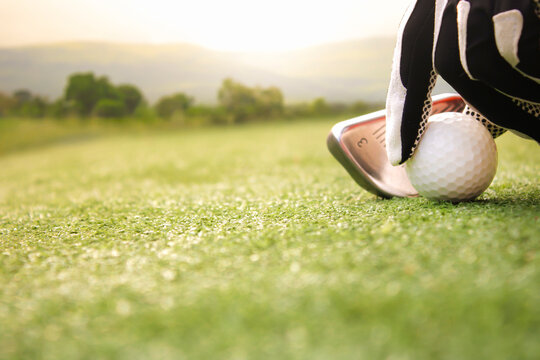 Hand placing golf ball on the grass.