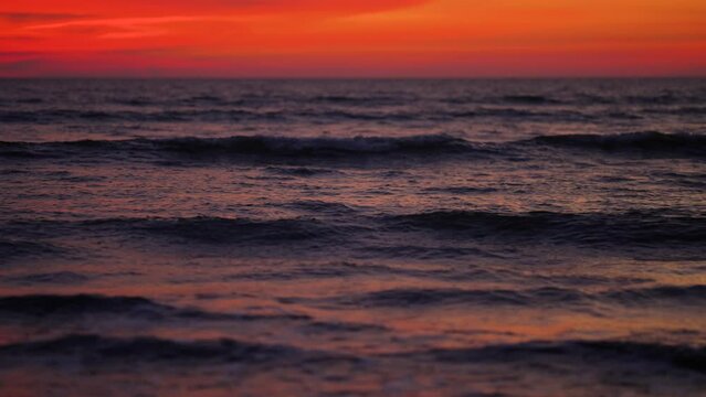 Immerse yourself in the vibrant hues of a colorful sunset at the beach, as waves rhythmically dance upon the shore in this captivating video