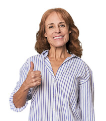 Redhead mid-aged Caucasian woman in studio smiling and raising thumb up