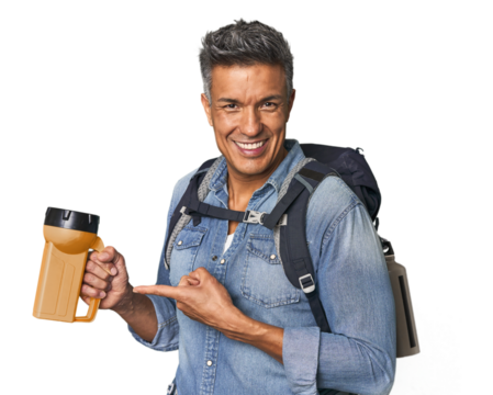 Hispanic trekker with backpack and flashlight smiling and pointing aside, showing something at blank space.
