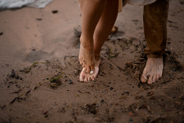 Feet of a young couple stand on the wet sand