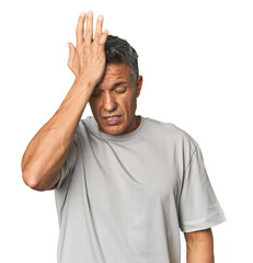 Middle-aged Latino man forgetting something, slapping forehead with palm and closing eyes.