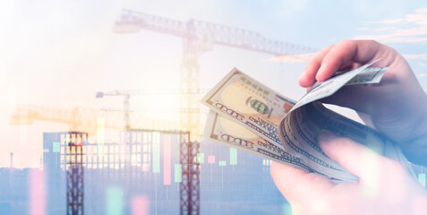 Builder hands with money. Banknotes near silhouette construction crane. Income from architectural...