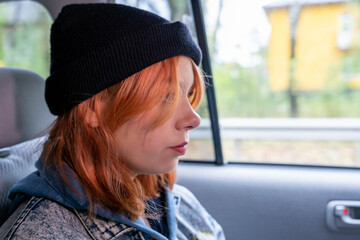  pretty girl with pink hair in a black knitted hat in the back seat of a car