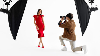 Male photographer capturing beautiful model in red dress