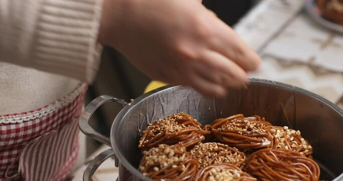 With meticulous care, the homemaker garnishes chebakia with sesame seeds, ensuring each piece is adorned with a touch of traditional Moroccan flavor