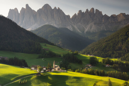 Santa Maddalena village in front of the Geisler or Odle Dolomites Group, Val di Funes, Trentino Alto Adige, Italy, Europe. Blue sky and green grass in Summer, August