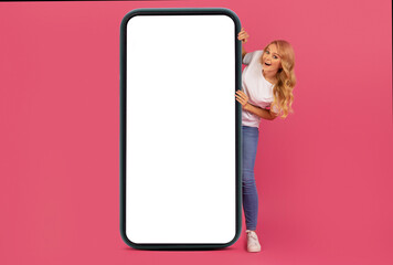 Smiling blonde lady presents large touchscreen of mobile phone, mockup