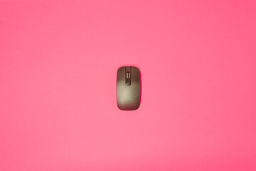 Black computer mouse on a pink background. Equipment for computers. Studio photo....