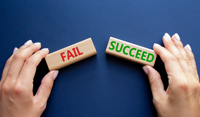 Fail or Succeed symbol. Concept word Fail or Succeed on wooden blocks. Businessman hand. Beautiful deep blue background. Business and Fail or Succeed concept. Copy space