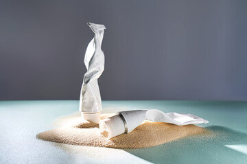 Two tubes of cream on the sand.