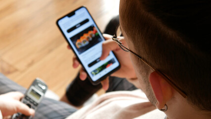 A young man choosing Japanese food in an online restaurant using a smartphone