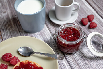 Homemade raspberry jam in glass jar, healthy breakfast with toast, raspberry jam, milk in cup and Italian espresso coffee, top view