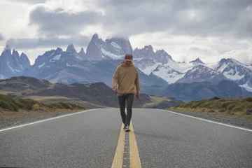 Fotobehang Cerro Chaltén A man walking on the road with a view of mountain Fitz Roy