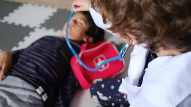 Siblings of 6 and 8 years old play pediatrician, doctors examining state of health with stereoscope and thermometer medical instruments. education, play in childhood and health with children.