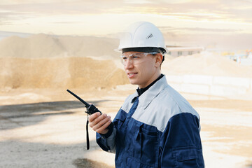 Concept open pit mine industry. Industrial worker use radio walkie talkie on sand quarry