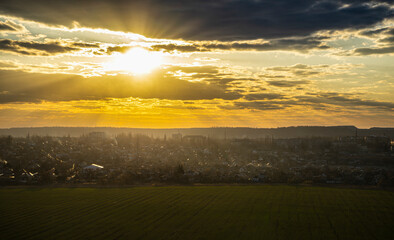 March sunset over the city and field in the rays of the spring sun