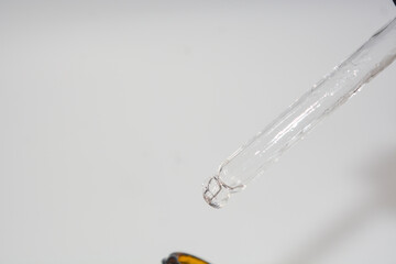 Cosmetic pipette with a drop close up on white background