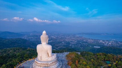 Naklejka premium Back view of statue big Buddha in on sunset sky, aerial photo by drone. Concept landmark of Phuket, travel in Thailand