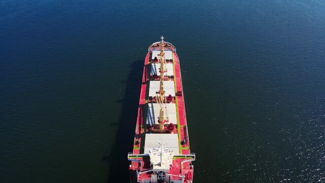 Bulk vessel for dry cargo cruising in sea for loading in industrial port, aerial shot