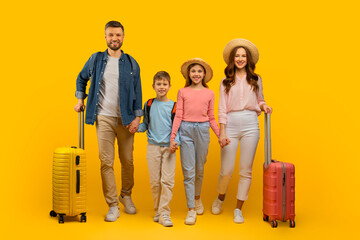 Happy Young Family Of Four Holding Hands And Walking With Suitcases