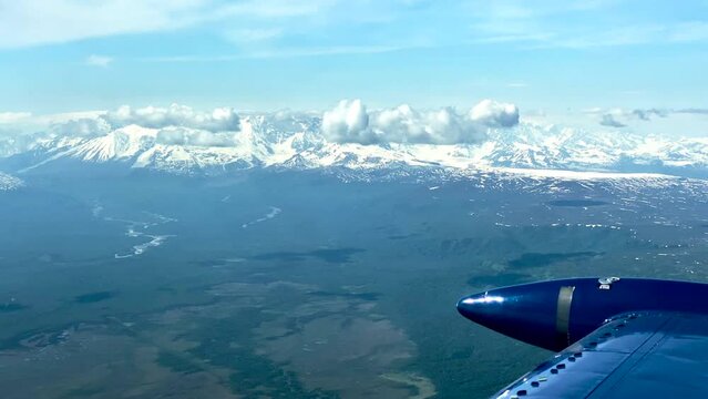 Beechcraft Bonanza airplane wingtip flies over Lake Clark Pass in Alaska. Mount Redoubt in the background. Small aircraft are only way to see many areas of Alaska.