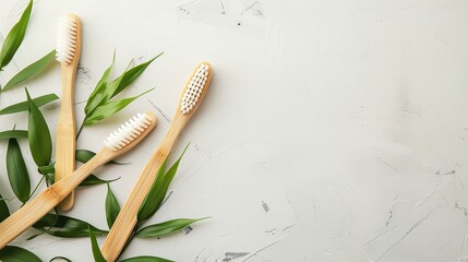 bamboo toothbrushes on a white table with green leaves and copy space
