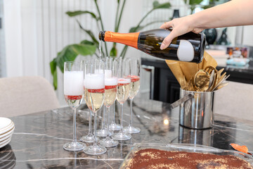 Champagne bottle being poured into a glass of champagne on the table