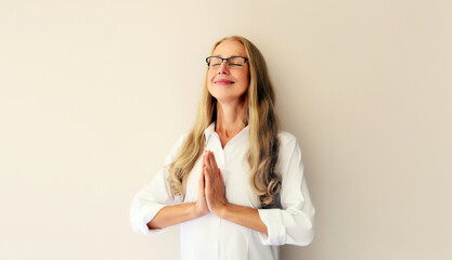 Calm relaxing healthy middle-aged woman meditates, practicing yoga on white background