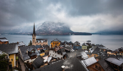 Hallstatt, Austria - The world famous Hallstatt, the Unesco protected lakeside town with Hallstatt Lutheran Church on a cold foggy day with snowy winter rooftops at Salzkammergut region
