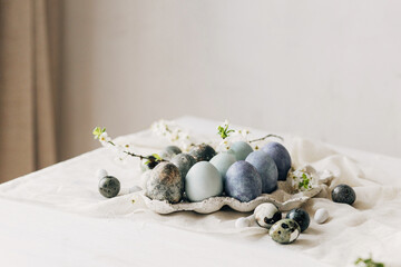 Stylish Easter eggs and spring flowers on rustic table. Happy Easter! Natural dye marble and blue...