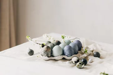Foto op Aluminium Stylish Easter eggs and spring flowers on rustic table. Happy Easter! Natural dye marble and blue eggs in tray and cherry blossoms. Happy Easter! Holiday minimal still life © sonyachny