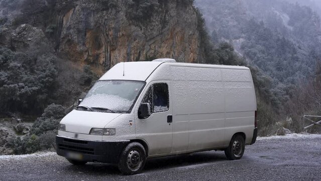 Camper van on the mountain while snow is falling in slow motion