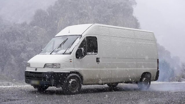 Camper van on the mountain while snow is falling in slow motion