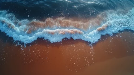  an aerial view of a body of water with a wave coming towards the shore and a person standing on a surfboard in the water. © Igor