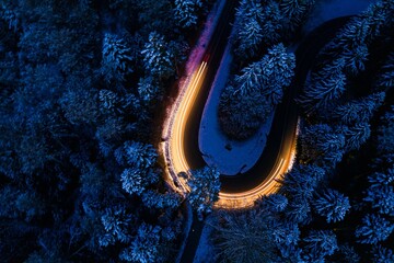 Road forming a curve in shape of an u-turn at night with cars painting the scenery
