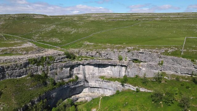 Drone footage shows green meadows and fields specific to Yorkshire in the Yorkshire Dales near Malham, Skipton, North Yorkshire UK