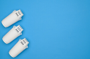 Layout: three new carbon filter cartridges for water purification on a blue background, top view. Concept of high-quality water purification from chlorine, lime, heavy metals. Purifying drinking water