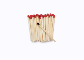 Burnt match on new matches on a white background with space for text. Close-up of red matches without a matchbox and one burnt match in the center.